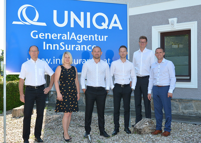 Das Team der UNIQA GeneralAgentur Innsurance vor einer großen Tafel mit dem Logo.
